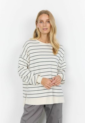 Maglietta a maniche lunghe colore crema con strisce blu navy, scollatura ampia, vestibilità morbida e polsini a coste, abbinata a pantaloni grigi.