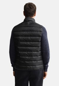 Schwarze gesteppte Steppweste mit horizontalen Steppnähten, hohem Kragen und glattem Finish; getragen über einem blauen, strukturierten Pullover.