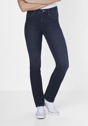 Dunkelblaue Slim-Fit-Jeans aus Stretch-Denim mit fünf Taschen, Gürtelschlaufen und dezenten Steppdetails. Kombiniert mit weißen Sneakers.