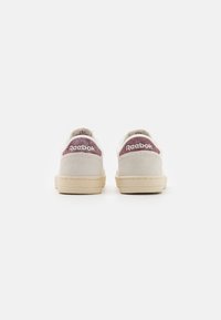 Buty sportowe Reebok z jasnoszarym zamszowym wierzchem, beżową gumową podeszwą i bordowymi akcentami na pięcie z logo.