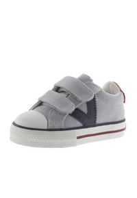 Scarpa in tela grigia con due strap in velcro, punta in gomma bianca, dettaglio blu navy e tacco rosso. Presenta un tessuto testurizzato e righe a contrasto.