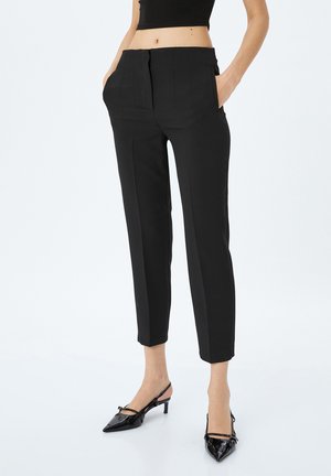 Pantalones negros ajustados con cintura alta, bolsillos laterales y un corte ceñido que termina justo por encima del tobillo, fabricados con una tela suave.