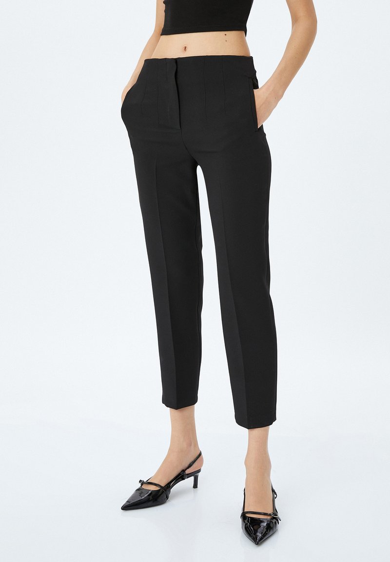Pantalones negros ajustados con cintura alta, bolsillos laterales y un corte ceñido que termina justo por encima del tobillo, fabricados con una tela suave.