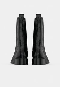 Crne gležnjače od sjajnog materijala s uzorkom krokodila, s niskim petama i elegantnim dizajnom.