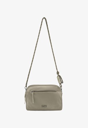 Kleine beige Umhängetasche mit vorderer Reißverschlusstasche, verstellbarem Kordelriemen und "Studio Berlin"-Logo auf der Vorderseite.