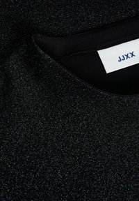 Black top with a subtle, sparkling texture. Round neckline with a folded edge. Interior label displays "JJXX" in blue on white background.