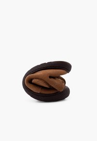 Chaussure en suède marron, au design plié, avec une semelle en caoutchouc noir et une surface texturée. Présente une sangle simple et des détails cousus.