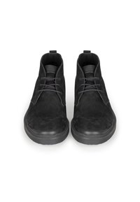 Botas negras hasta el tobillo hechas de ante con un acabado mate, que cuentan con una punta redondeada, cordones en la parte frontal y una tira en el talón para tirar.