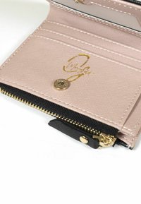 Rosa texturerad plånbok med guld-logotyp, flera kortfack och ett svart dragkedjefack. Har detaljer med guldhardware och sömnad.