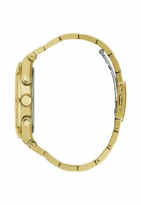 Montre en métal doré avec un cadran rond, plusieurs boutons, une lunette texturée et un bracelet à maillons. Présente un fermoir en métal argenté et des sections polies.