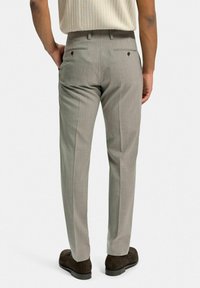 Slim-fit grå byxor i en texturerad tyg, två bakfickor och en ren, skräddarsydd silhuett. Stylad med mörkbruna skor.