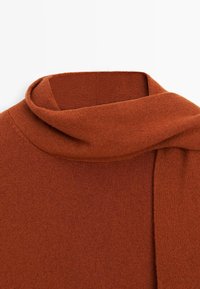 Ein rostfarbener gestrickter Pullover mit umgeschlagenem Kragen auf einem weißen Hintergrund.