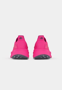 Ténis rosa brilhante vistos de trás, com logótipos Adidas pretos nas abas dos calcanhares e solas cinzentas texturizadas.