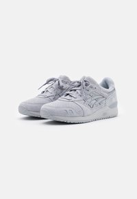 Light gray athletic shoes made of suede and mesh, featuring perforations, textured laces, and a padded collar for comfort.