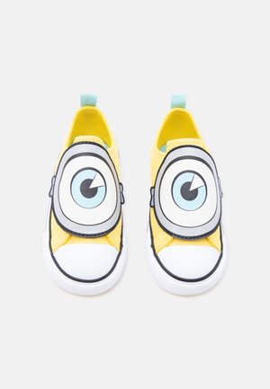 Paire de chaussures jaunes à enfiler pour enfants avec de grands yeux de dessin animé sur le dessus et des embouts en caoutchouc blanc.