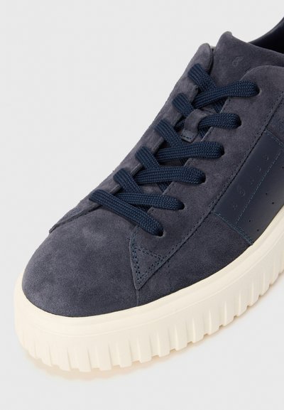 Navy blue suede sneaker with thick white ridged sole and matching blue laces on a plain light background.