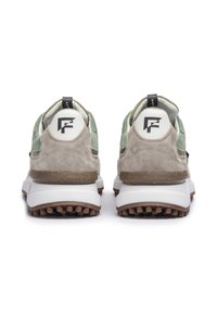 Un paio di sneaker caratterizzate da un mix di suede grigio chiaro e verde, suola bianca spessa con dettagli marroni testurizzati e logo circolare sul tallone.