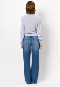 Lichtpaarse, gebreide trui met een ronde hals en lange mouwen, gecombineerd met hoge taille, wijdvallende, vervaagde blauwe denim jeans.