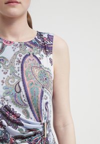 Ärmlös klänning i ett lätt tyg med ett färgglatt paisleymönster som har lila, turkosa och rosa detaljer, rynkad vid midjan med en metallisk detalj.