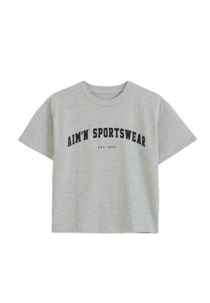 Siva skrajšana majica iz mehkega bombaža, ki ima kratke rokave in krožni izrez. Spredaj je napis "AIM'N SPORTSWEAR" v krepki črni pisavi.
