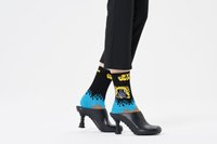 Des escarpins à plateforme noirs avec un bout ondulé et une semelle texturée. Des chaussettes colorées avec des flammes bleues et un design graphique "Star Wars".