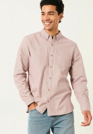 Rot-weiß karierte Button-Up-Bluse mit langen Ärmeln, einer Brusttasche und Holzknöpfen. Kombiniert mit blauen Jeans.