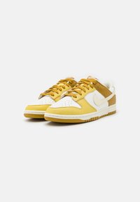 Żółte i białe skórzane trampki o niskim profilu, z perforowanym przodem, podwyższoną podeszwą środkową i grubą gumową podeszwą. Posiadają tonowane sznurowadła i logo.