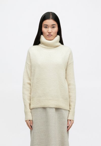 Κρέμα μακρυμάνικη μπλούζα με ψηλό γιακά και ριγωτή περιφέρεια, κατασκευασμένη από μαλακό ύφασμα. Χαλαρή εφαρμογή, με πλήρους μήκους μανίκια και ελάχιστες λεπτομέρειες.