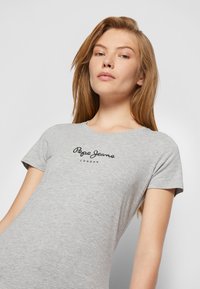 T-shirt grigia in cotone con collo rotondo, maniche corte e logo "Pepe Jeans London" in nero centrato sul petto.