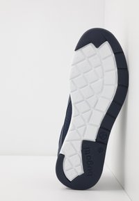 Navy mesh sneaker with a white textured rubber sole, featuring a tread pattern and embossed logo on the side, designed for comfort and grip.