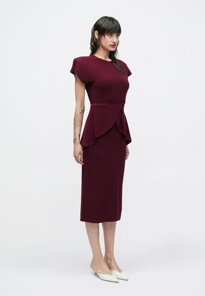 Dopasowana bordowa sukienka z krótkimi, usztywnionymi rękawami, detalem w pasie typu peplum oraz paskiem. Gładki materiał o subtelnym połysku.