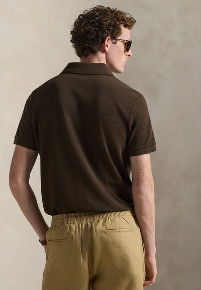 Brown short-sleeve polo shirt with a textured fabric, paired with light tan elastic-waist pants featuring two back pockets.