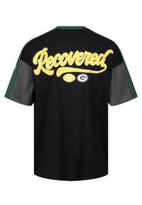 T-shirt noir avec des accents verts, portant le mot "Récupéré" en cursive jaune au dos, accompagné d'un graphique de football et d'un logo.