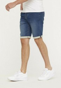 Denim shorts met opgerolde cuffs, middelblauwe wassing, vijf-pocket ontwerp, gecombineerd met witte sneakers, die een casual uitstraling laten zien.