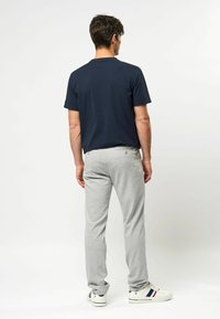 Navy cotton T-shirt paired with light grey sweatpants, featuring a relaxed fit. Footwear is white sneakers with navy and red accents.
