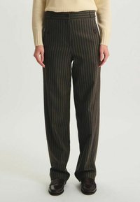 Pantalons marron à rayures avec une taille haute, des jambes droites et des détails de boutons à la taille, fabriqués à partir d'un tissu texturé.