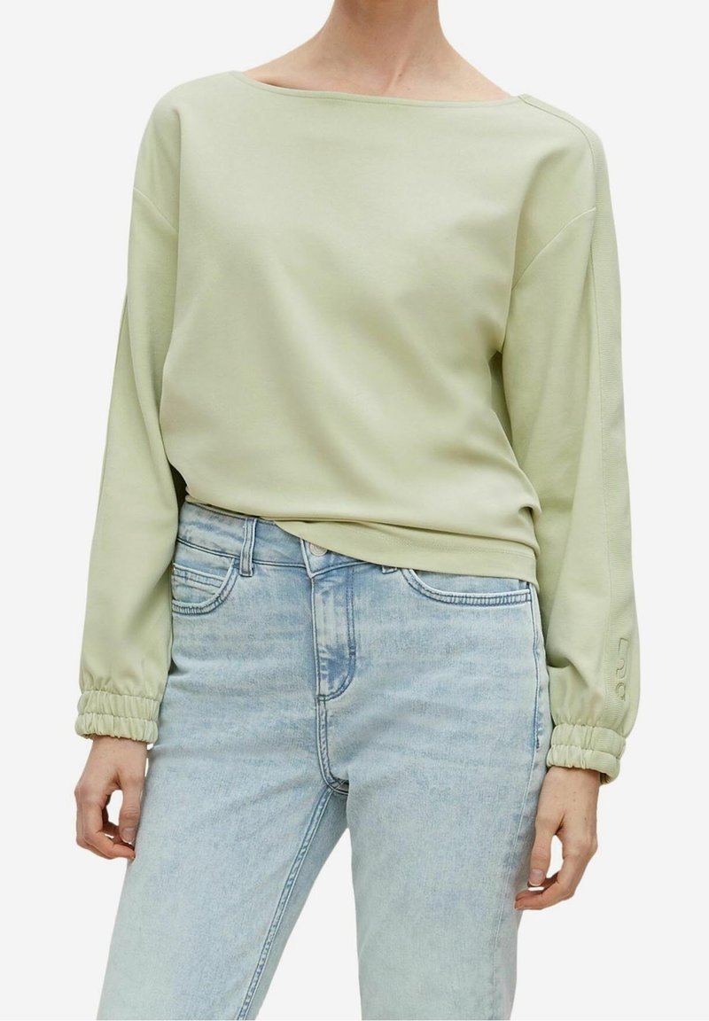 Lichtgroene sweatshirt met een ruime halslijn, elastische manchetten en een relaxte pasvorm, gecombineerd met lichtblauwe spijkerbroek. Glad van textuur.