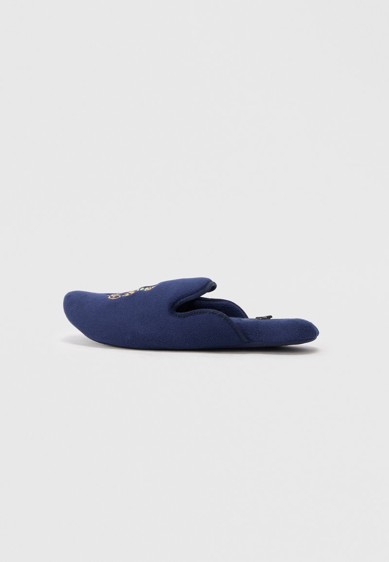 Chausson bleu marine à enfiler avec motif brodé sur le dessus, tissu doux et arrière ouvert pour un enfilage facile.