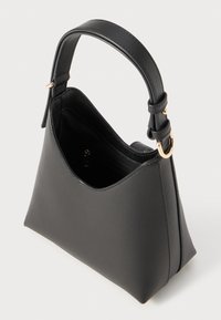Sac à main en cuir noir avec un design structuré et angulaire, doté d'une seule bandoulière réglable et d'un accent en métal doré.