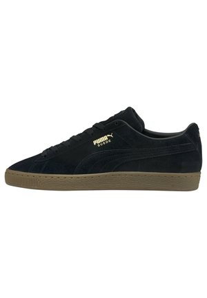 Baskets basses Puma en daim noir avec semelle en gomme, logo Puma doré et détails en daim sur le côté.