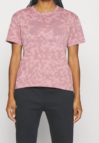 Tričko s krátkým rukávem, kulatým výstřihem v tlumené růžové barvě, se strukturálním vzorem a výrazným tónovaným logem "Under Armour".