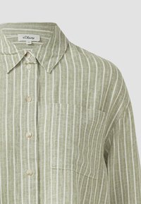 Chemise en lin vert clair avec des rayures blanches verticales, une poche avant, un col boutonné et des boutons blancs.