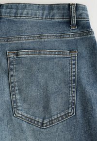 Denimová tkanina s svetlomodrým umývaním. Obsahuje jednu zadnú vrecko s kontrastným švom. Hladký povrch s vystuženými švami.