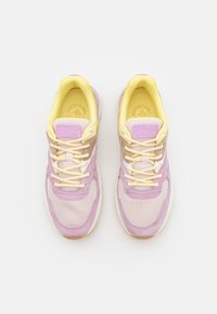 Purple and yellow sneakers with mesh and suede materials. Features laces, padded collar, and a logo tag on the tongue. Textured detailing throughout.