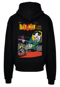 Svart hettegenser med et tegneserie-lignende trykk av Batman, Jokeren, og en fargerik bakgrunn med gule og røde accenter.