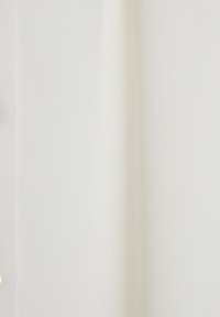 Witte stoffen paneel met een gladde textuur, voorzien van knopen langs één rand en een lichte glans die licht reflecteert. Minimalistisch ontwerp.