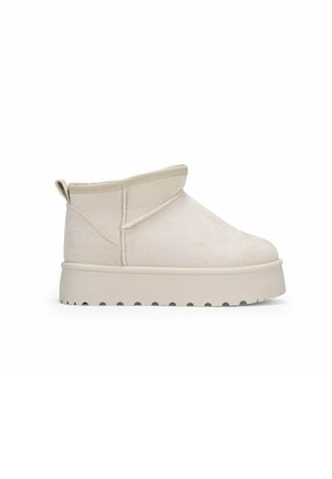 Bottes beige à la cheville en daim doux avec un bout arrondi, un col replié et une semelle épaisse et striée. Pas de quincaillerie ou de motifs visibles.