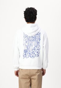 Felpa bianca con un design grafico blu caratterizzato da forme astratte ed elementi floreali sul retro. Tessuto morbido, stile pullover, con cappuccio.