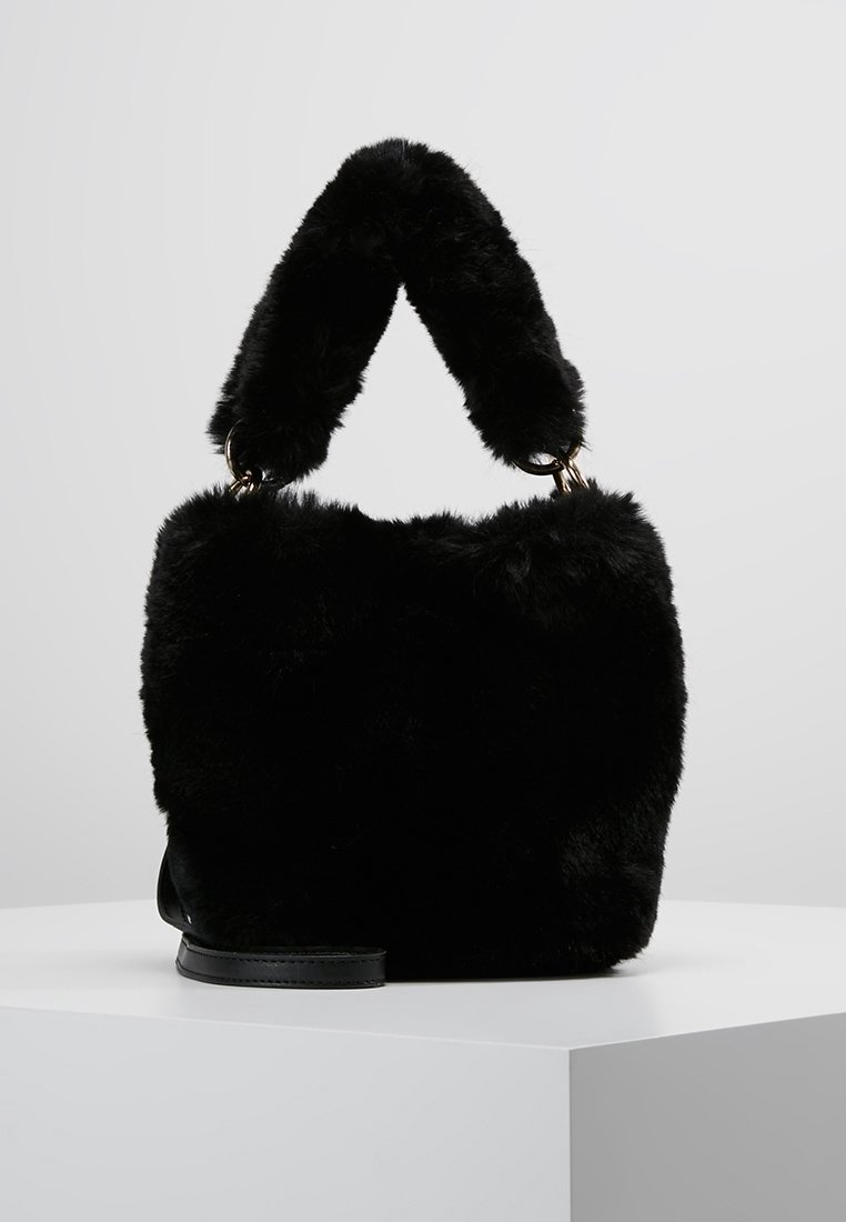 Czarna torebka z sztucznego futra o miękkiej, puszystej teksturze, zaokrąglonym górnym uchwycie i płaskiej podstawie. Złote akcenty metalowe.