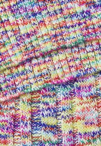 Gros plan d’un tissu tricoté multicolore avec un motif panaché en rangées de fils rouges, jaunes, bleus, violets, blancs et verts.